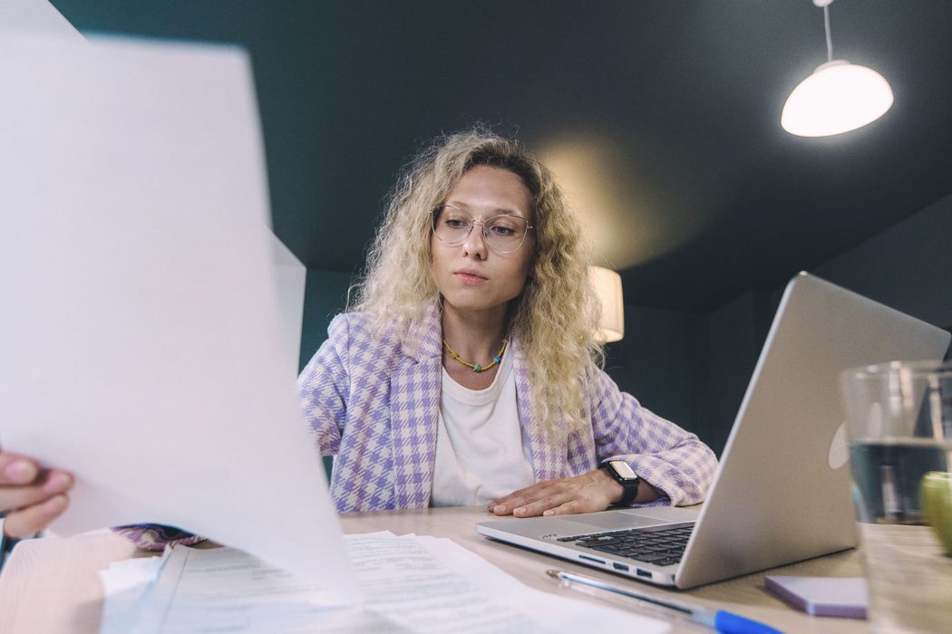 Person reviewing tax documents next to a laptop at a desk