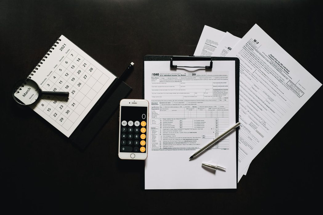 Federal tax return forms, a calculator and a pen on a wooden desk